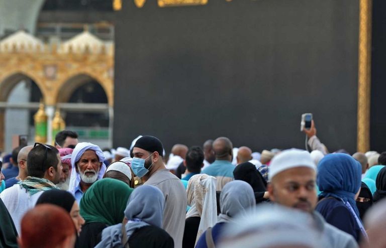 أحد زوار بيت الله الحرام يرتدي كمامة