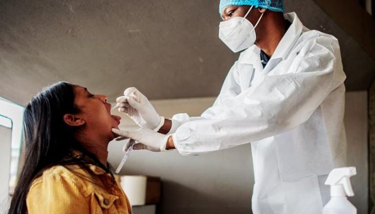 عامل صحي يأخذ مسحة من امرأة لإجراء اختبار كورونا