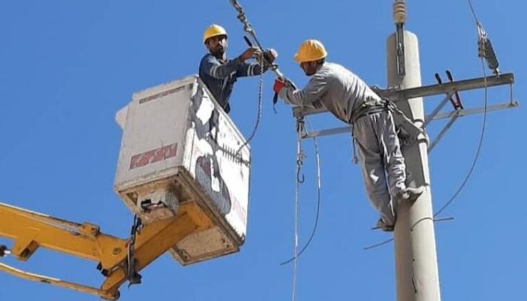 موظفان إيرانيان يحاولان إصلاح عطب كهربائي