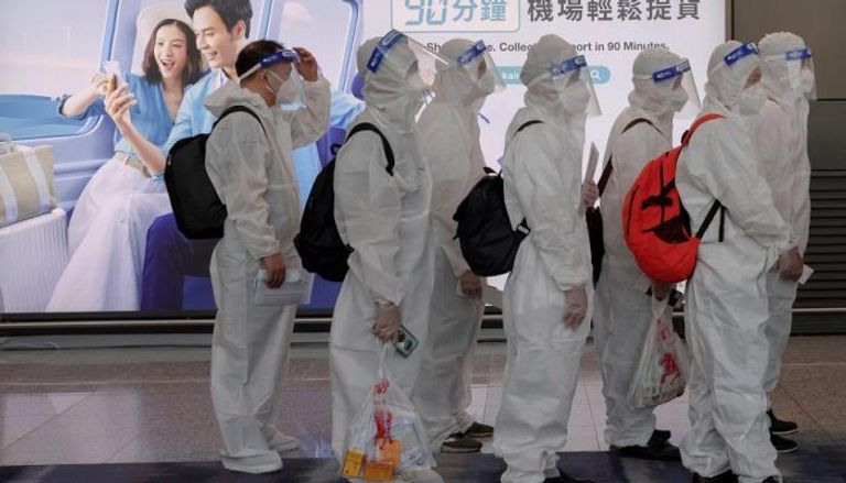 مسافرون يرتدون ملابس واقية من فيروس كورونا في مطار هونج كونج