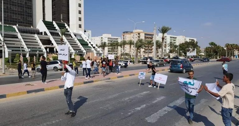 شباب يحملون لافتات ضمن مظاهرات تحديد المصير في ليبيا 