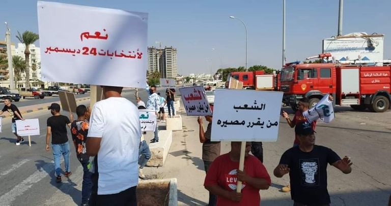 شباب يحملون لافتات ضمن مظاهرات تحديد المصير في ليبيا 