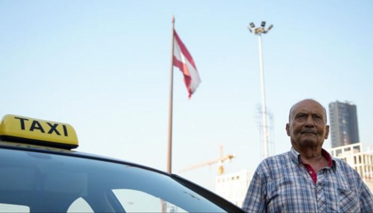 العلم اللبناني يرفرف فوق سائق لسيارة أجرة سبعيني لبناني في وسط بيروت - رويترز
