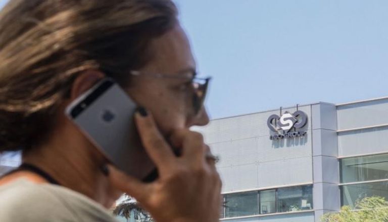 امرأة تستخدم هاتفها أمام مبنى شركة NSO الإسرائيلية