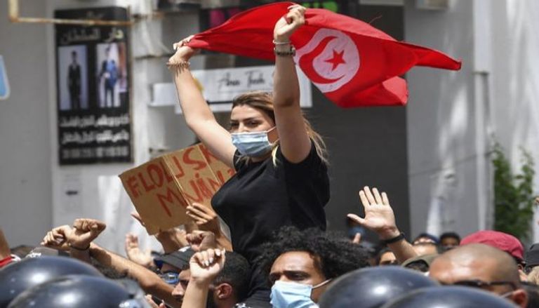 فتاة تونسية تحمل علم بلادها في احتجاجات ضد الإخوان