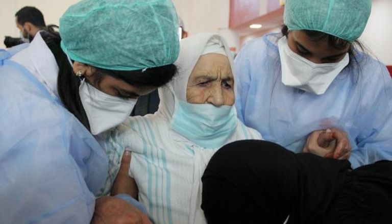 ممرضتان تساعدان مسنا مغربيا قبل تلقي لقاح كورونا