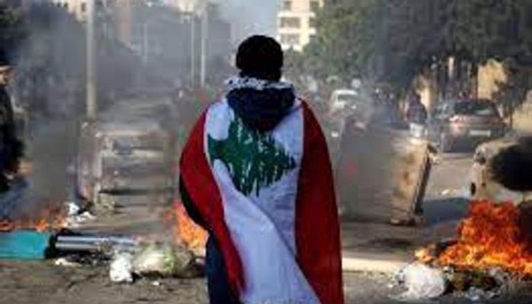 متظاهر يحمل علم لبنان خلال احتجاجات ضد النخبة السياسية