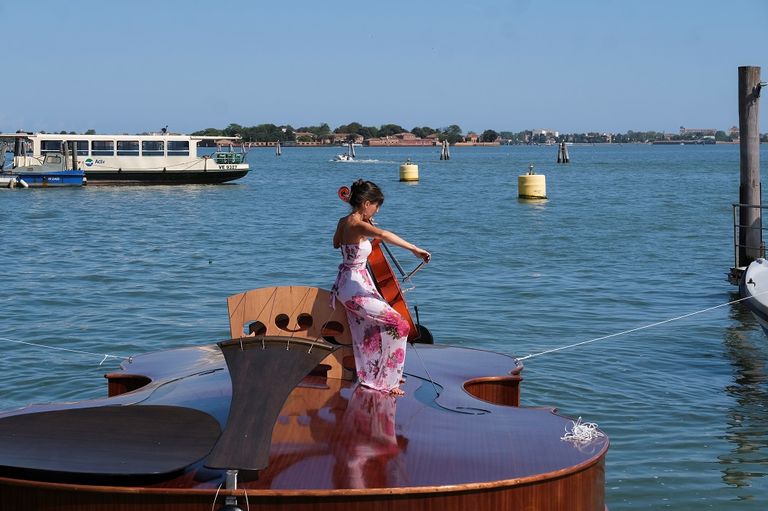 عازفة التشيلو ترتدي فستان سهرة خلال الرحلة التجريبية لقارب تكريم ضحايا كورونا