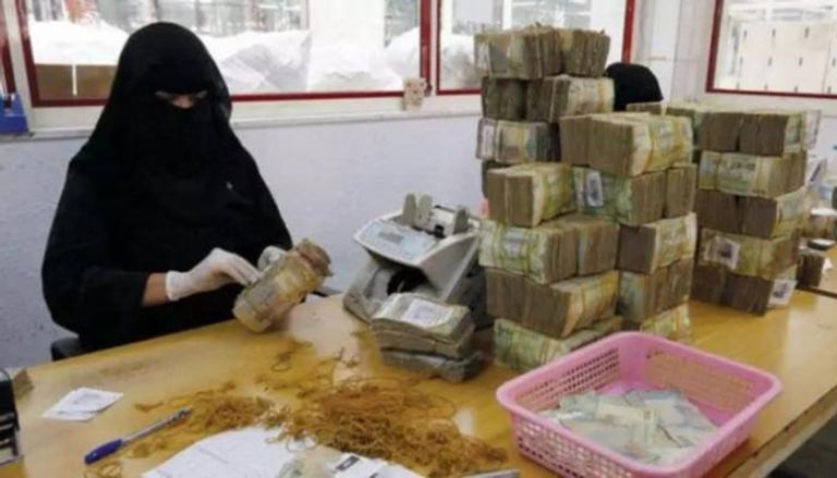 موظفة تقوم بفرز عملات ورقية من الريال اليمني في أحد البنوك