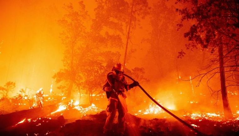 رجل إطفاء يصارع النيران بخرطوم مياه