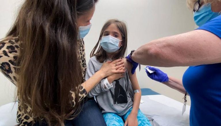 فتاة صغيرة بصحبة والدتها تحصل على التطعيم