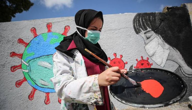 فتاة فلسطينية ترسم جدارية عن كورونا