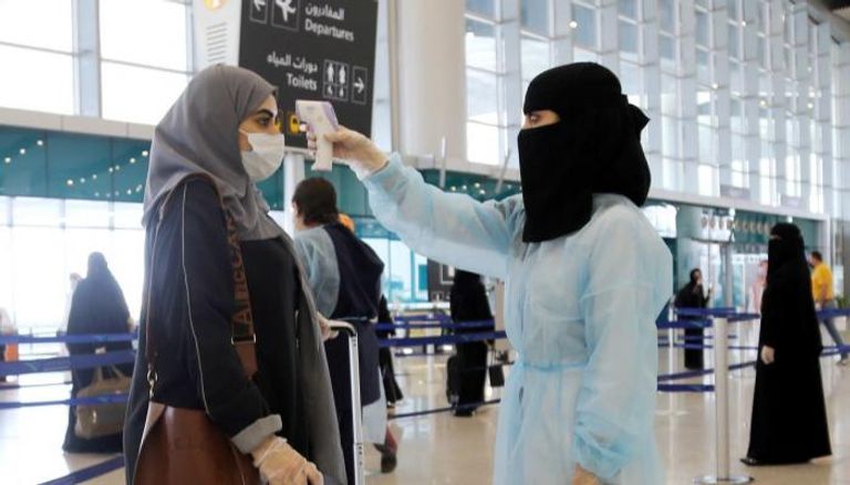 عاملة صحية تجري قياساً لحرارة فتاة في السعودية
