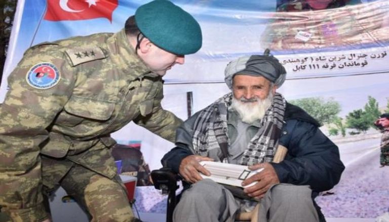 ضابط تركي يوزع المساعدات على مسن أفغاني