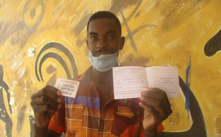 مواطن من تمنراست يحمل بيد شهادة تلقيح وبالأخرى تذكرة المسابقة حملة تلقيح ضد فيروس كورونا بولاية تمنراست الجزائرية