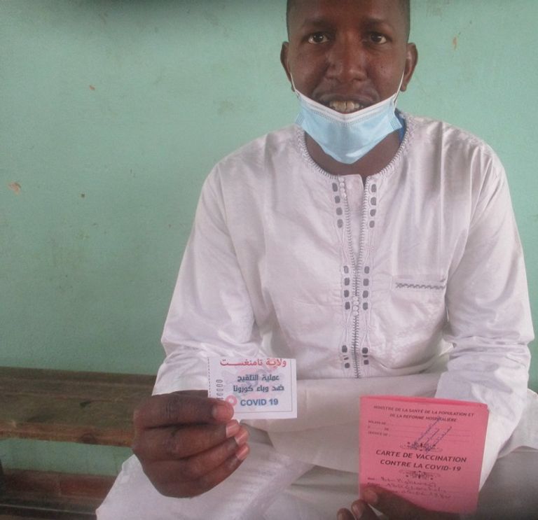 مواطن من تمنراست يحمل بيد شهادة تلقيح وبالأخرى تذكرة المسابقة حملة تلقيح ضد فيروس كورونا بولاية تمنراست الجزائرية