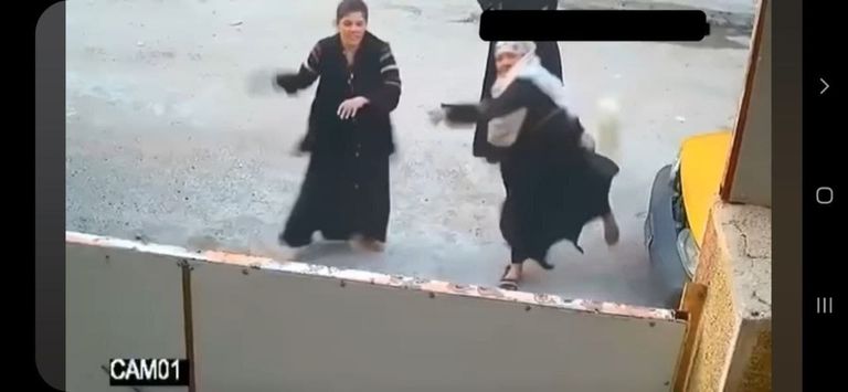 صورة ملتقطة من مقطع فيديو لنساء يهاجمن أحد المنازل بالحجارة