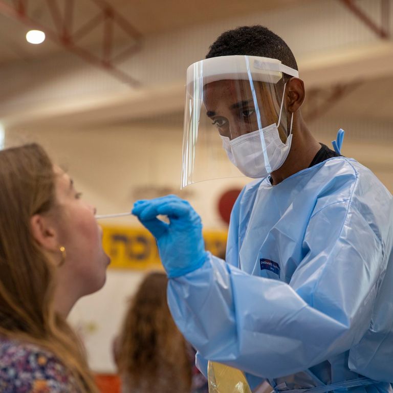 طبيب يرتدي بدلة واقية أثناء الحصول على مسحة فيروس كورونا من امرأة - أرشيفية