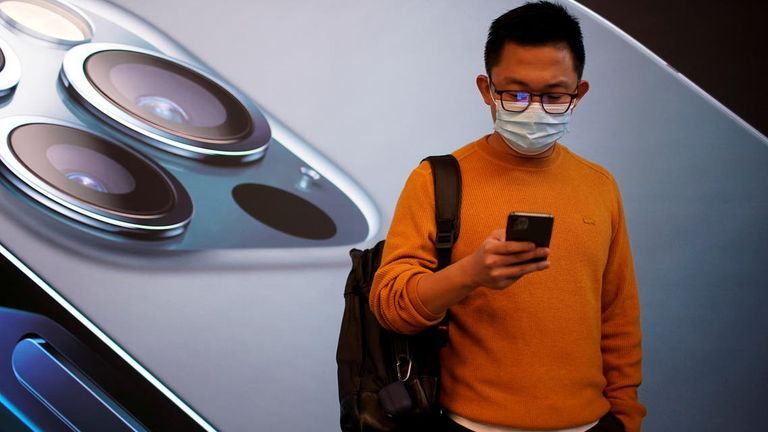 شاب يقف خلف ملصق إعلان هاتف آيفون هاتف آيفون من أبل - أرشيفية