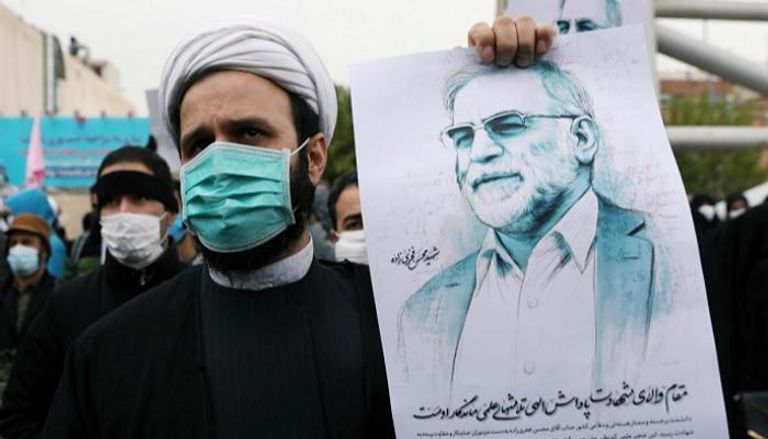 أحد الإيرانيين يحمل صورة للعالم الإيراني زاده