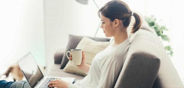 سيدة تعمل على الحاسوب في منزلها وبجوارها طفلة تدرس