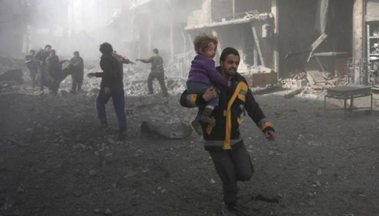 سوري يحمل طفلا عقب قصف على إحدى المناطق السورية