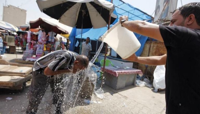عراقي يخفف حر الصيف عن صديقه بسكب الماء عليه