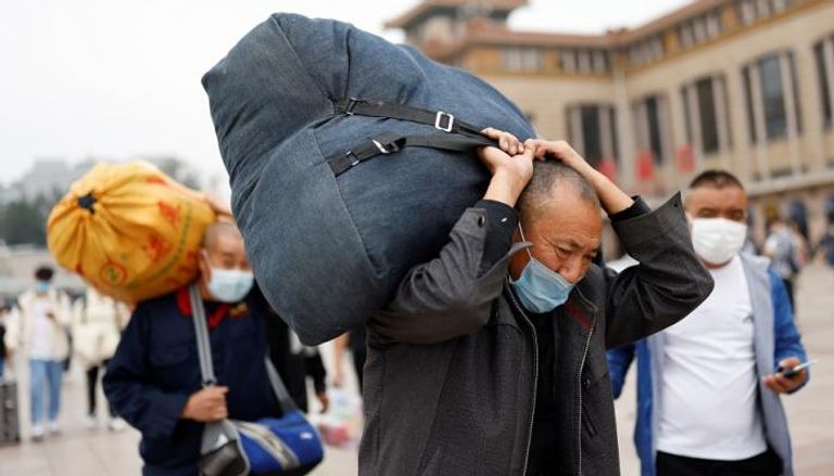 صينيون يحملون حقائبهم في محطة قطارات بكين