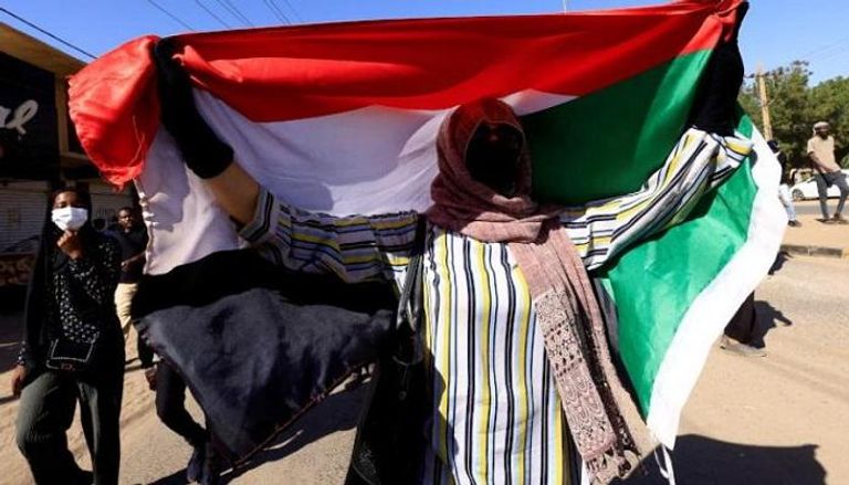 متظاهرة سودانية تحمل علم بلادها
