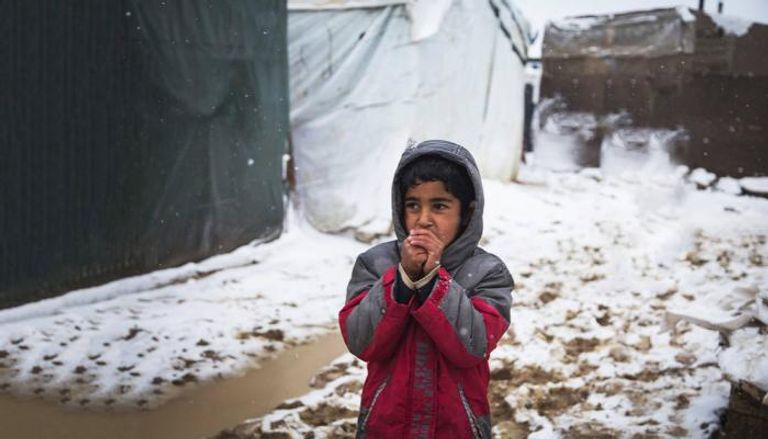 طفل لاجئ يحاول تدفئة يديه