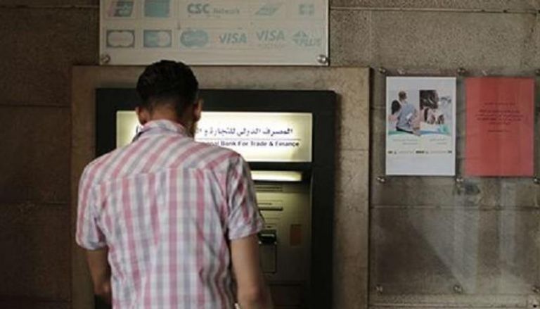 سوري أمام ماكينة صراف آلي تتبع المصرف الدولي للتجارة