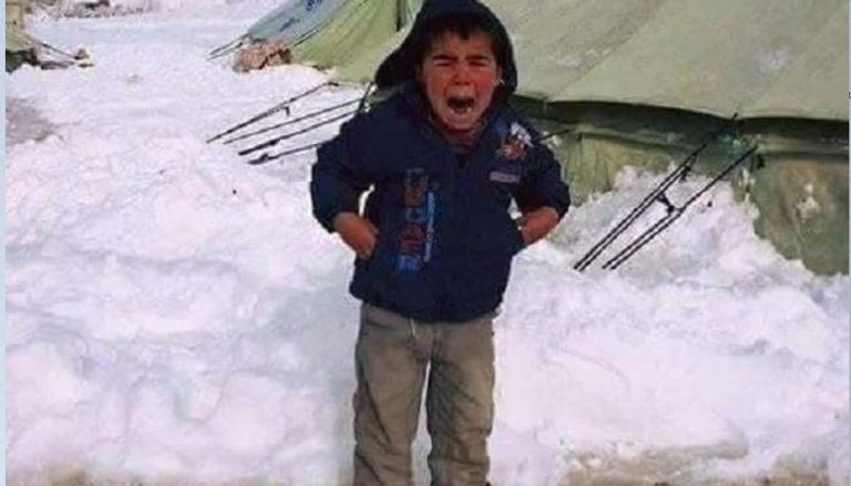 طفل يبكي نتيجة شعوره بالبرد بجوار مخيم 