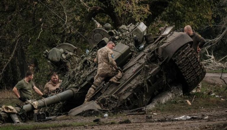 جنود أوكرانيون فوق دبابة روسية مدمرة