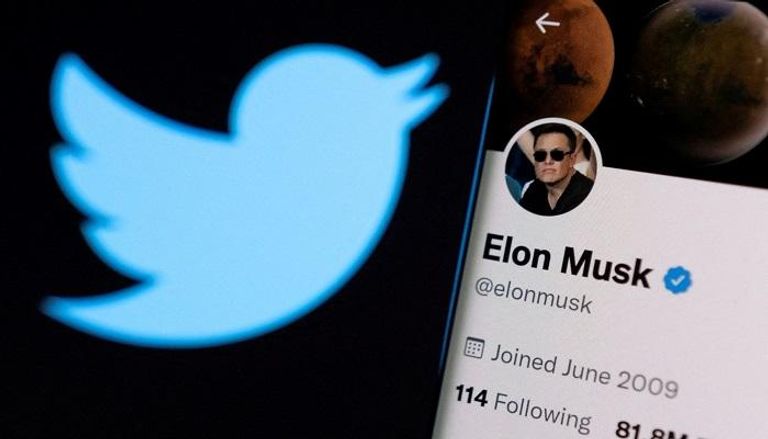 حساب Elon Musk على تويتر على هاتف ذكي أمام شعار Twitter - رويترز