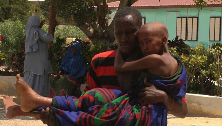 صومالي يحمل طفلاً مصابًا جراء اشتباكات بين الجيش وحركة الشباب
