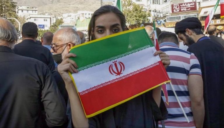 إيرانية ترفع علم بلادها خلال احتجاجات مناهضة للنظام