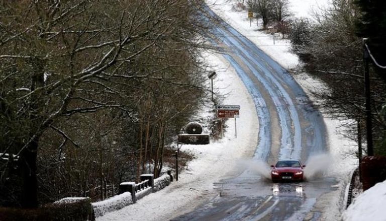 سيارات تسير على طريق مغطى بالثلوج في بريطانيا خلال شتاء 2021 - رويترز