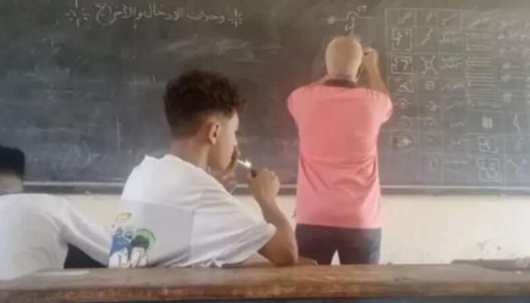 طالب يشعل سيجارة داخل الفصل