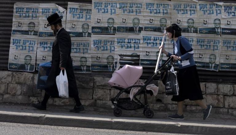 زوجان إسرائيليان يسيران قرب صور مرشحين
