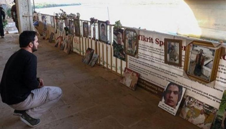 شخص يجلس أمام شواهد ولافتات لبعض ضحايا مجزرة سبايكر
