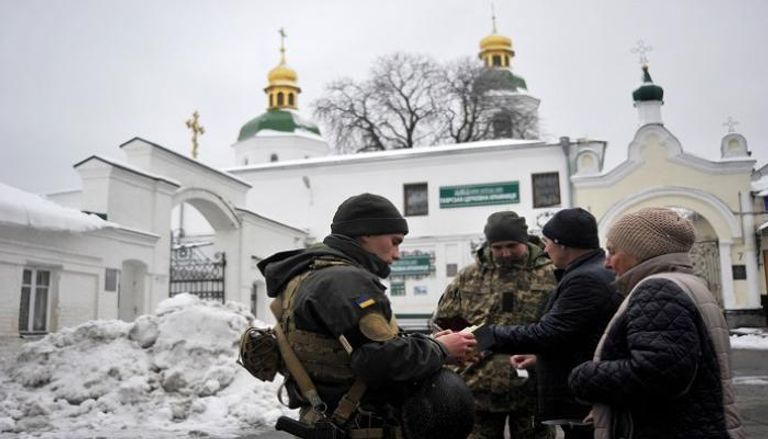 جنود من دائرة الأمن الأوكرانية يفحصون وثائق زوار دير كييف 