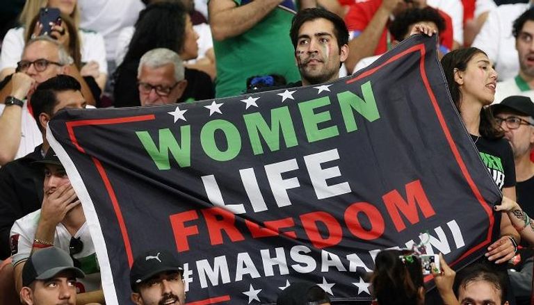 لافتة يحملها مشجع إيراني في الدوحة تطالب بحرية المرأة في إيران 