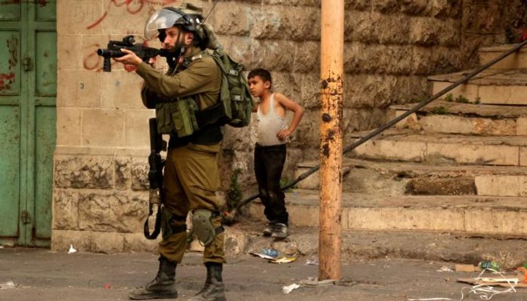 جندي إسرائيلي يصوب سلاحه نحو فلسطينيين بالضفة الغربية- أرشيفية