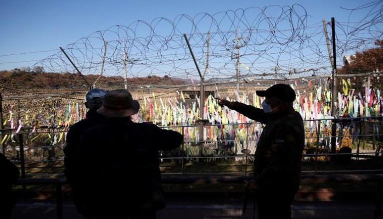 رجال ينظرون لسياج عسكري قرب المنطقة منزوعة السلاح بين الكوريتين 