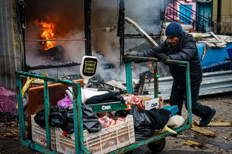 مواطن أوكراني يمر أمام مبنى اشتعل جراء القصف الروسي إجلاء مصاب أوكراني جراء القصف الروسي