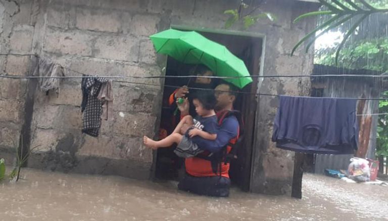 رجل يحمي طفلة من الفيضانات