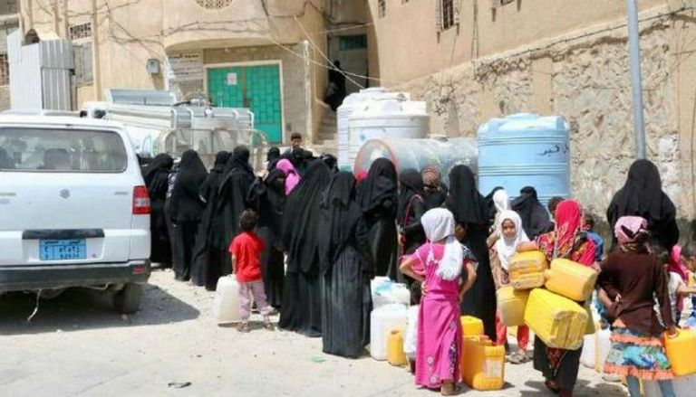 نساء وفتيات يقفن في طابور طويل للحصول على المياه