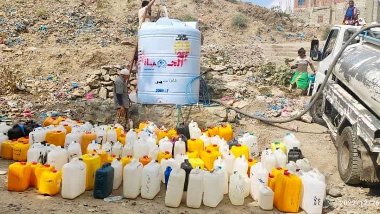 نساء وفتيات يقفن في طابور طويل للحصول على المياه