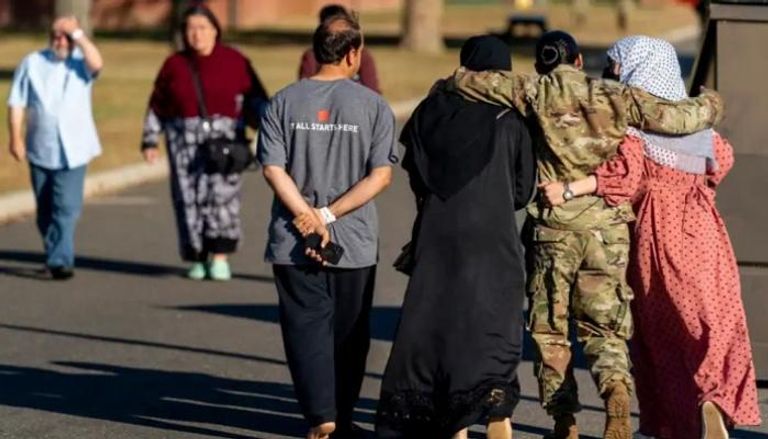 عضوة في الجيش تضع ذراعيها حول امرأتين لاجئتين أفغانيتين في مخيم بولاية نيوجيرسي 