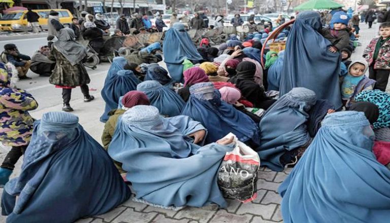 نساء وأطفال ينتظرون توزيع خبز مجاني أمام مخبزة بالعاصمة الأفغانية